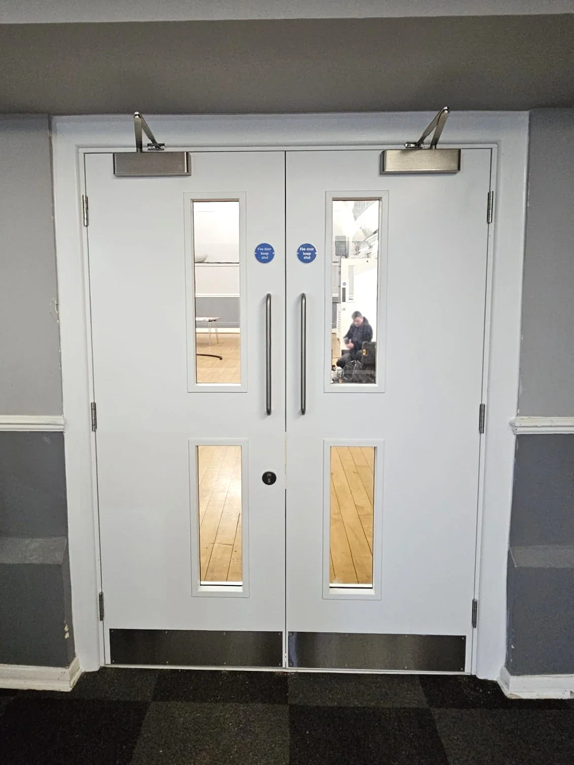 White double doors with glazed panels and overhead closers
