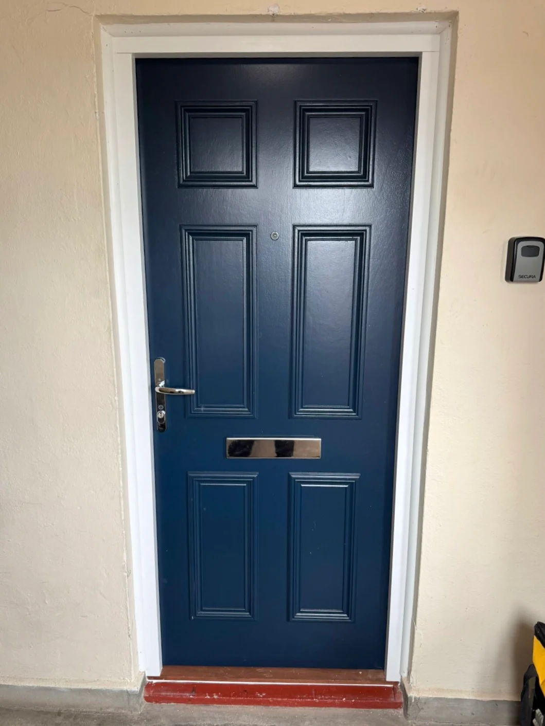 Installed blue residential entrance door with white frame
