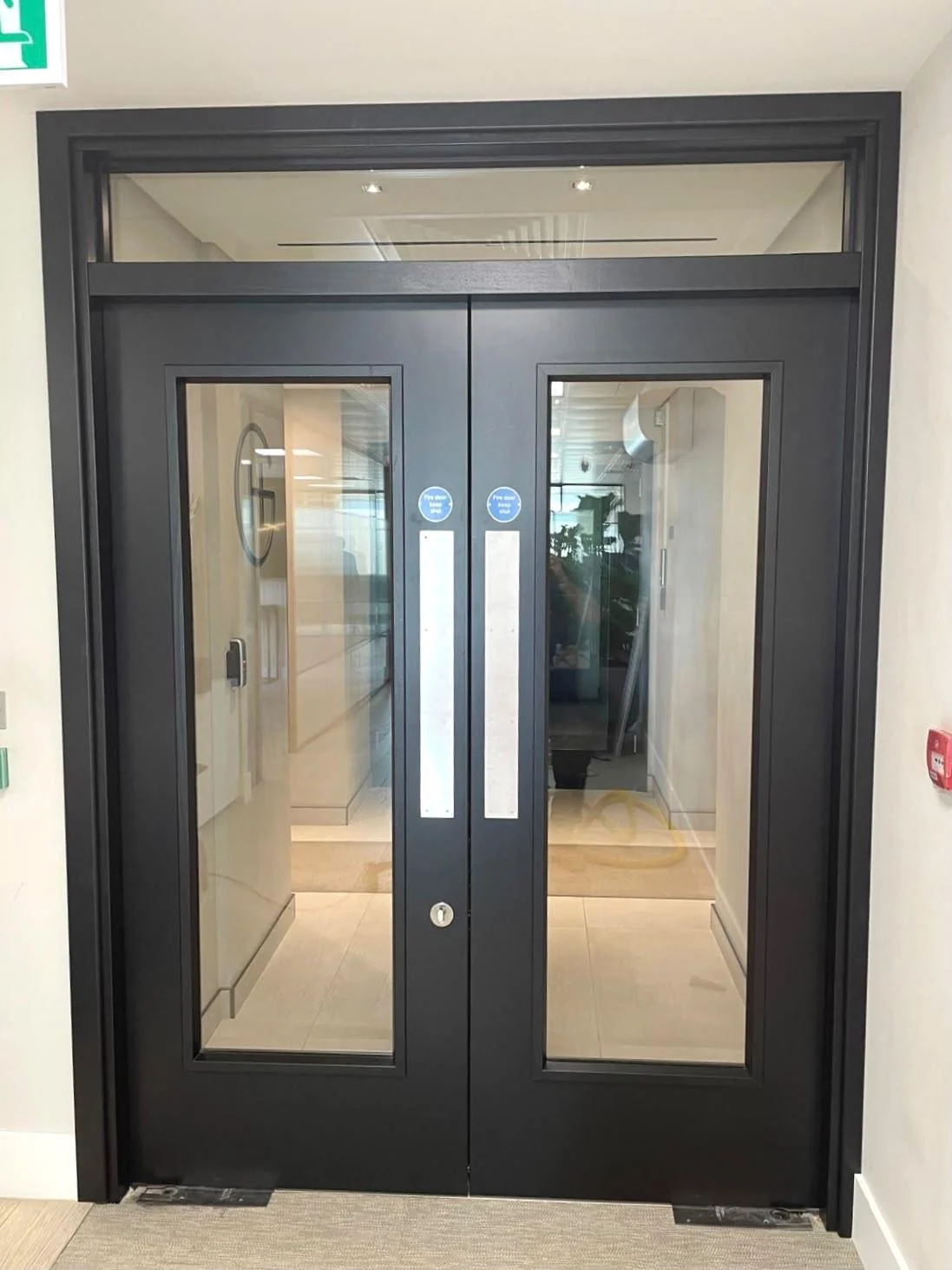 Installed grey glazed double doors with matching frame and overpanel
