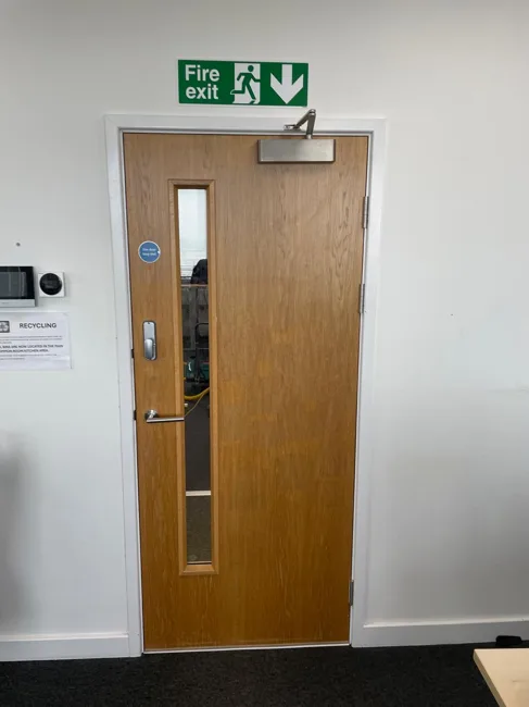 Timber-finish single door with vision panel and overhead closer