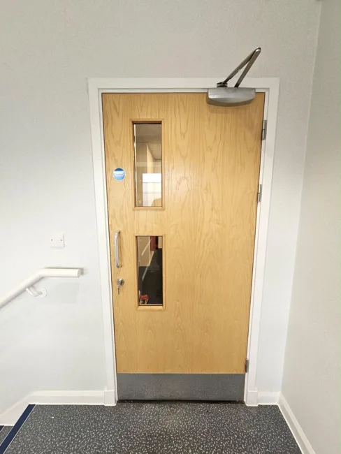 Timber-finish single door beside a stair handrail